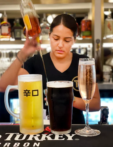 A bartender pouring drinks at the bar