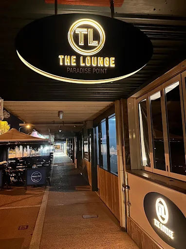 The Lounge frontage lit up at night on The Esplanade, with the illuminated Paradise Point signage above the entrance