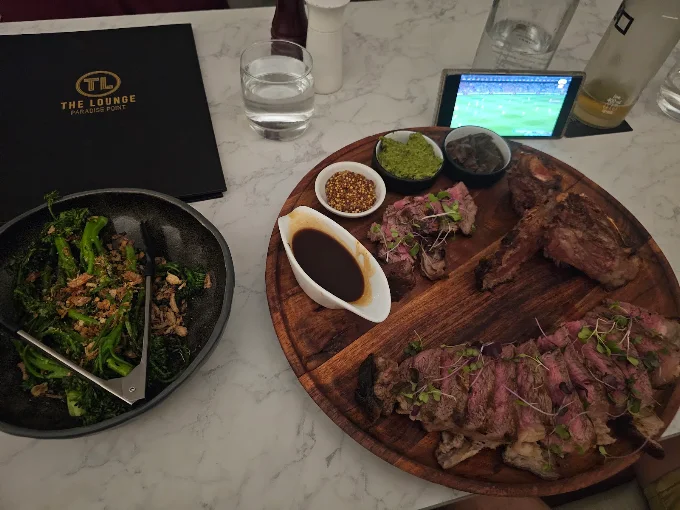 A sharing board of steak and salad on a marble table