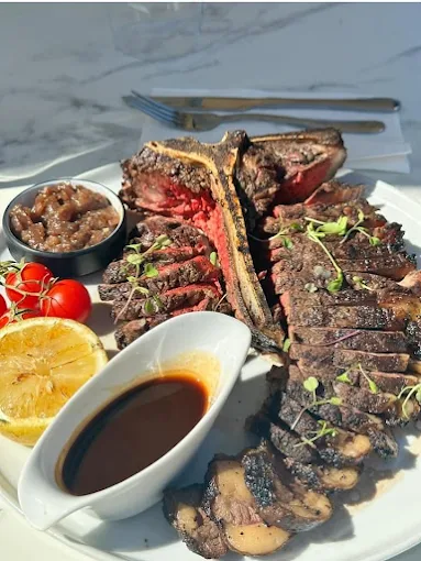 Sliced steak on the bone with red wine jus and lemon